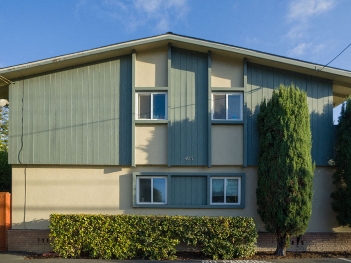 a green and white house with a tree in front of it